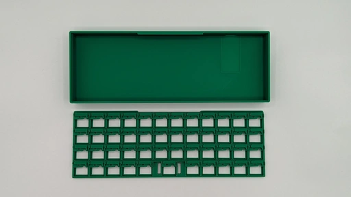 A Sleepy Keeb in green with the plate face down and the case open